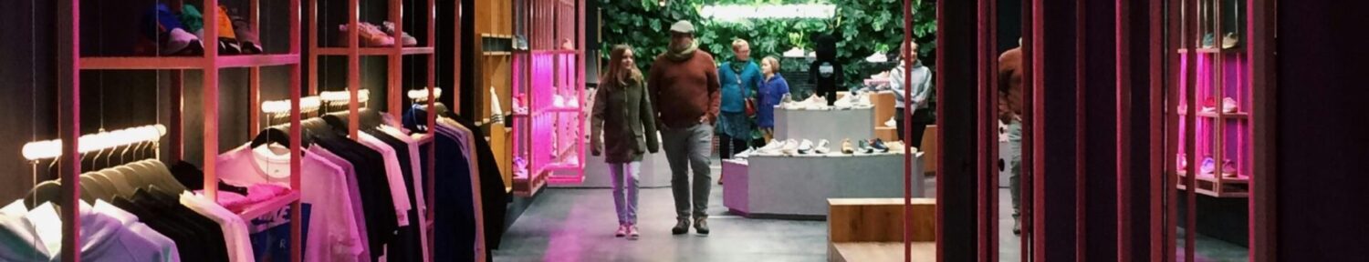 Interior of a modern clothing store in Antwerp, featuring neon pink lights and a sleek design.